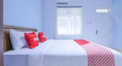 a white bed with red pillows in a bedroom at OYO 1755 De'balcon Accomodation Near Ngurah Rai Airport in Ubud