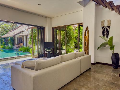 a living room with a white couch and a tv at Villa Blubambu in Seminyak