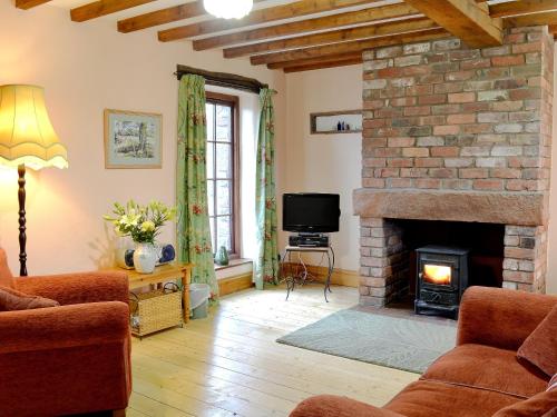 un soggiorno con camino in mattoni e TV di Stable Cottage - B6062 a Pooley Bridge