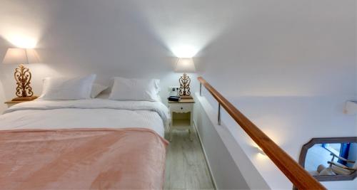 a white bedroom with a bed and a staircase at Desiterra Resort & Spa in Fira