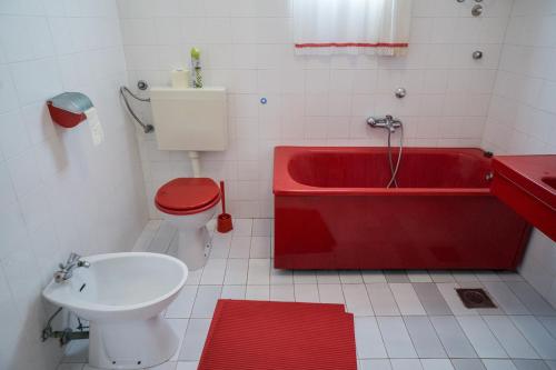 a bathroom with a red tub and a toilet at Apartments PODATOK 4 in Primošten