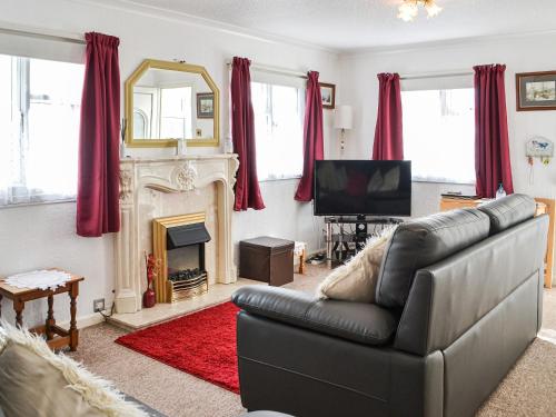 a living room with a couch and a television at Enjoy Your Stay Cottage in Bessingby