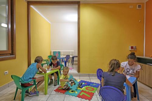 a group of children sitting at tables in a room at Hotel Residence La Pertica in Tremosine Sul Garda