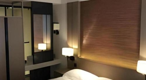 a bedroom with a bed and a mirror and lights at V8 Ziyuangang Hotel in Guangzhou