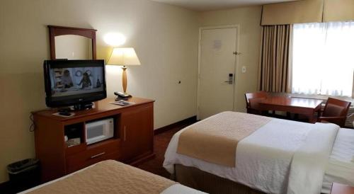 a hotel room with two beds and a flat screen tv at Airport Inn in Boise