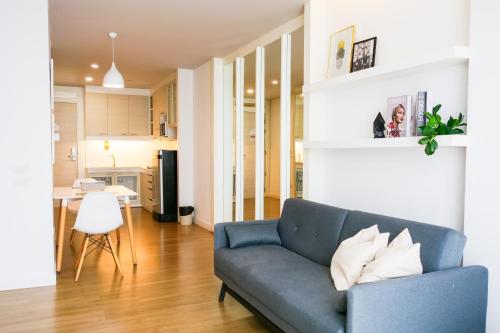 a living room with a blue couch and a kitchen at THE KANNAS Hotel & Serviced Apartment, Chiang Mai SHA Certified in Chiang Mai