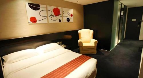 a hotel room with a bed and a chair at Noble Park Hotel in Hong Kong