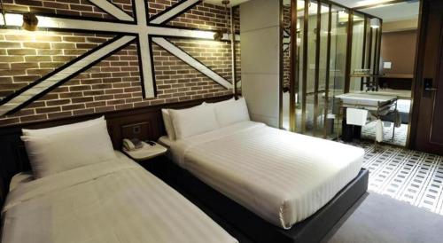 a bedroom with two beds and a bathroom with a sink at King's Hotel in Hong Kong