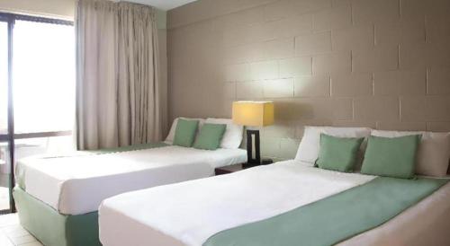 阿皮亚Insel Fehmarn Hotel的一间设有两张绿色和白色床铺的客房