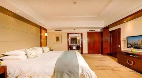 a bedroom with a large bed and a flat screen tv at Gaosu New Century Hotel International Anhui in Hefei