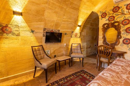 a room with a bed and chairs and a tv at Walnut House in Goreme