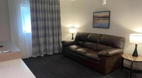 a living room with a brown leather couch and two lamps at Best Western Lake Lucille Inn in Wasilla