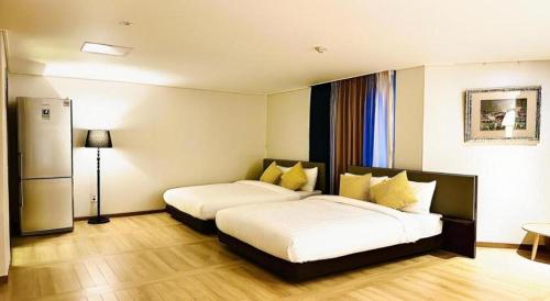 a hotel room with two beds and a refrigerator at Hotel One Byeonsan in Buan
