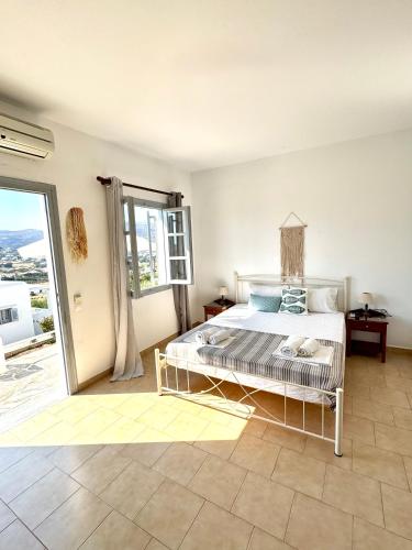 a bedroom with a bed and a large window at Kirki Rooms on the Hill in Parikia