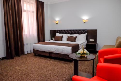 una camera d'albergo con letto e sedia rossa di ZhanaOtel Hotel ad Aqtau