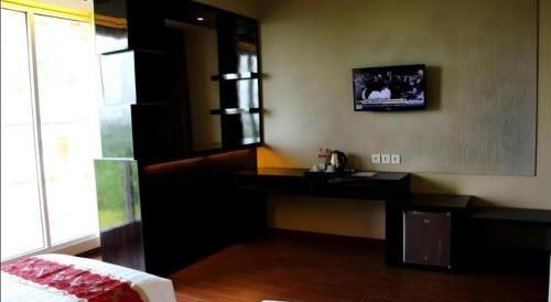 a bedroom with a desk and a television on the wall at The Belagri Hotel and Convention in Sorong