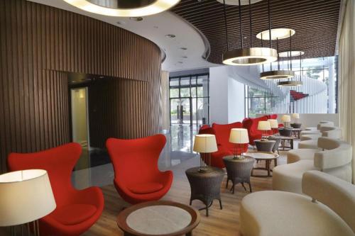 a waiting room with red chairs and tables and lamps at Brits Hotel Karawang in Karawang