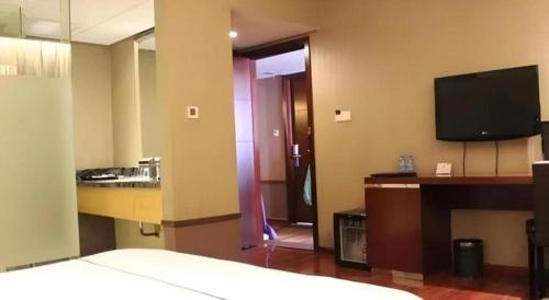 a hotel room with a bed and a television at Yiwu Baiheng Hotel in Yiwu