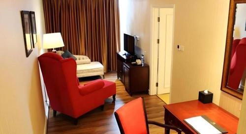 a living room with a red chair and a couch at Adimulia Hotel Medan in Medan