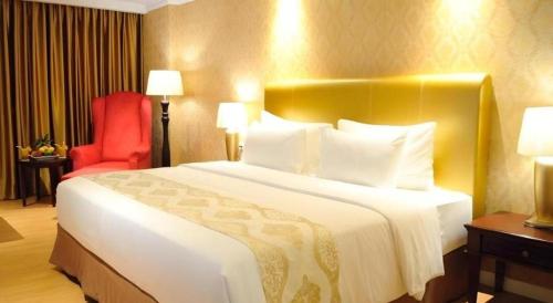 a hotel room with a large bed and a red chair at Adimulia Hotel Medan in Medan