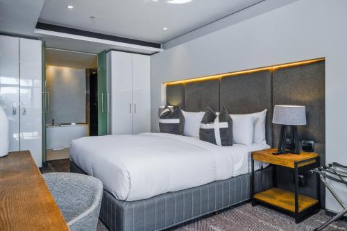 a hotel room with a large bed and a chair at The Capital 15 on Orange Hotel & Spa in Cape Town