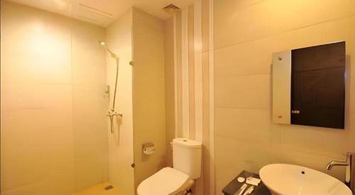 a bathroom with a toilet and a tv on the wall at Nutana Hotel in Gili Trawangan