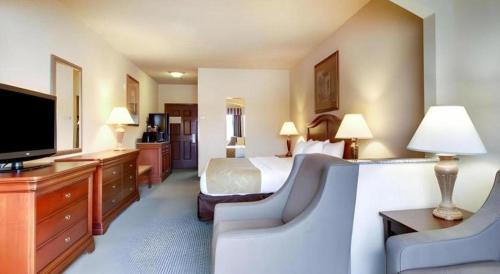 a hotel room with a bed and a flat screen tv at Clarion Suites Vidalia Riverfront in Vidalia