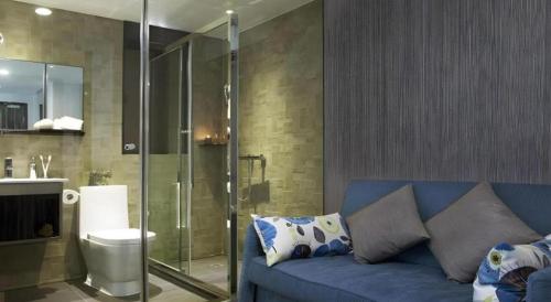 a bathroom with a blue couch in front of a shower at M1 North Point Hotel in Hong Kong