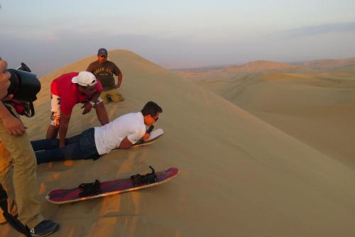 a group of people in the desert with a snowboard at Hotel Las Flores in Ica