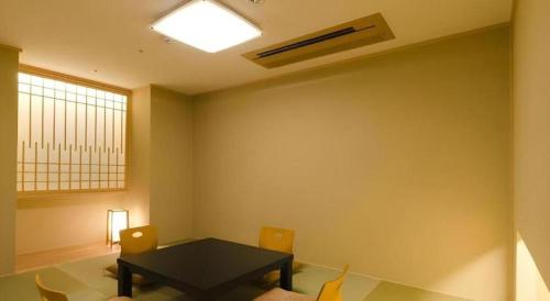 a dining room with a black table and chairs at Kannawa Onsen Hotel Sansuikan in Beppu