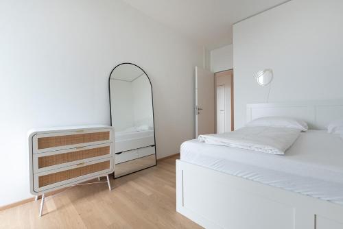 a white bedroom with a white bed and a mirror at Hoch hinaus - Pool am Dach, Rundum Balkon mit Traumaussicht in Vienna