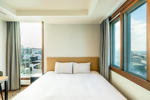 a bedroom with a bed and a large window at Check Inn Hotel in Jeju
