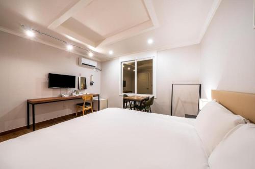 a bedroom with a bed and a desk and a television at Check Inn Hotel in Jeju