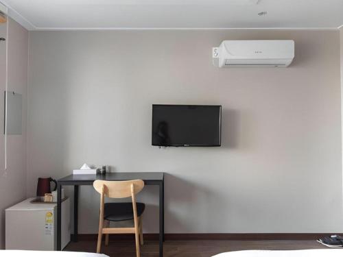 a desk with a chair and a television on a wall at Check Inn Hotel in Jeju