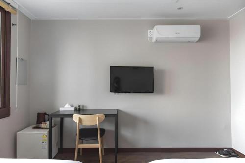 a desk with a chair and a television on a wall at Check Inn Hotel in Jeju