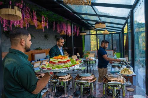 Un hombre sosteniendo una bandeja de comida sobre una mesa. en Seclude Kasauli, Himachal Pradesh, en Kasauli
