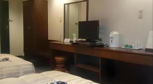 a hotel room with a desk with a television and a bed at Hotel Honjin in Kumamoto