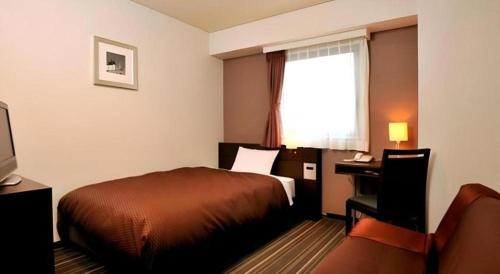 a hotel room with a bed and a desk and a window at Daini Fuji Hotel in Nagoya
