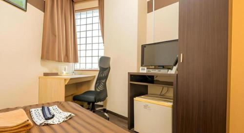 a bedroom with a bed and a desk with a television at Mimatsu Hotel in Mito