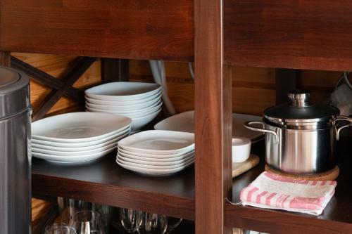 a cabinet with plates and dishes on a shelf at Romantic cozy house Kirzacinas pirts with sauna close to seaside in Skulte