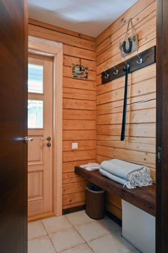 a bathroom with a wooden wall with a bench and a door at Romantic cozy house Kirzacinas pirts with sauna close to seaside in Skulte