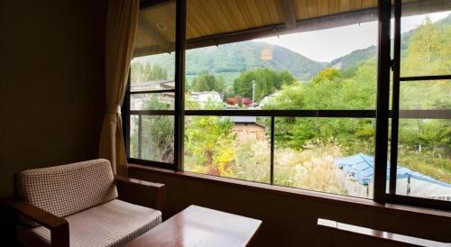 a room with a window with a chair and a table at Hirayu Prince Hotel in Takayama