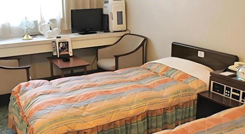 a bedroom with a bed and a desk with a computer at Hotel Abest Aomori in Aomori