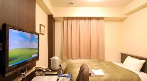 a hotel room with a flat screen tv and a bed at Chino Station Hotel in Chino