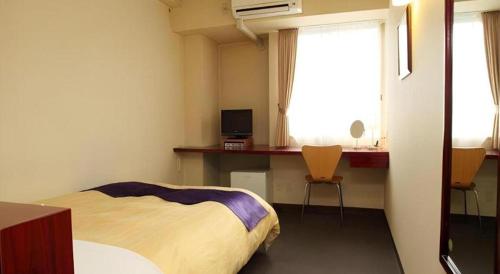 a bedroom with a bed and a desk and a window at Hotel 1-2-3 Kofu Shingen Onsen in Kofu