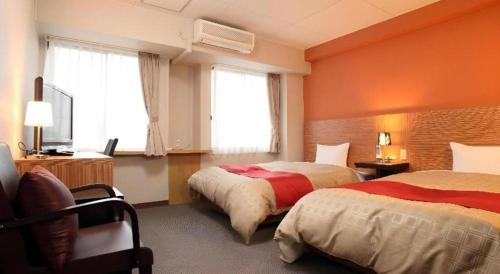 a hotel room with two beds and two windows at Hotel 1-2-3 Kofu Shingen Onsen in Kofu
