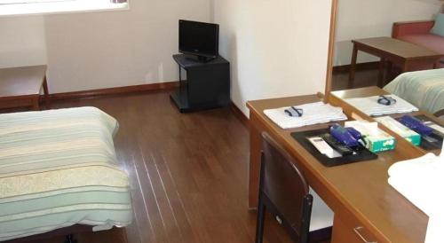 a room with a desk with a bed and a mirror at Petit Hotel Key West Club in Naha
