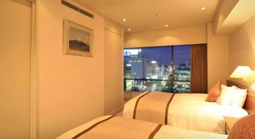 a hotel room with two beds and a window at Hotel Harvest In Yonago in Yonago