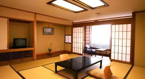 a living room with a table and a tv at Hotel Tokoen in Yonago