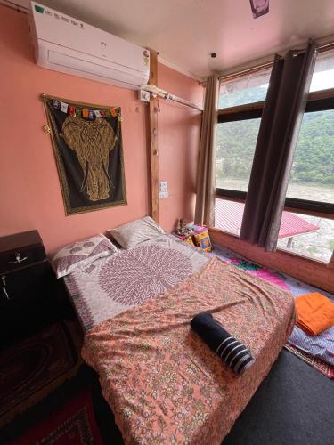 a bedroom with a bed in a room with windows at Shanti Shanti Ganga View in Rishīkesh